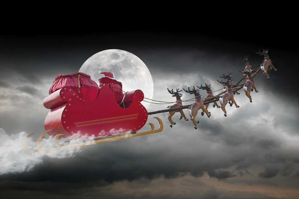 Santa Claus riding a sleigh led by reindeers on a cloudy night